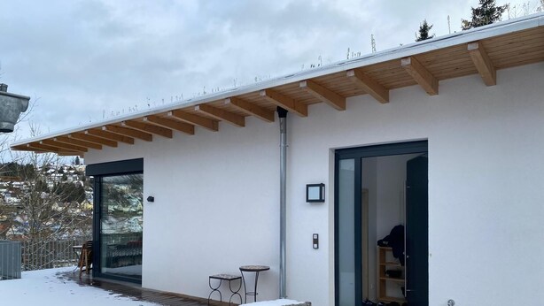 A modern building with a wooden roof, a glass door, and a small outdoor seating area. - Warm magic in the heart of the Black Forest (Titisee-Neustadt)