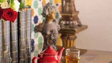 A table with a teapot, a glass of tea, a notebook, and a vase of roses.