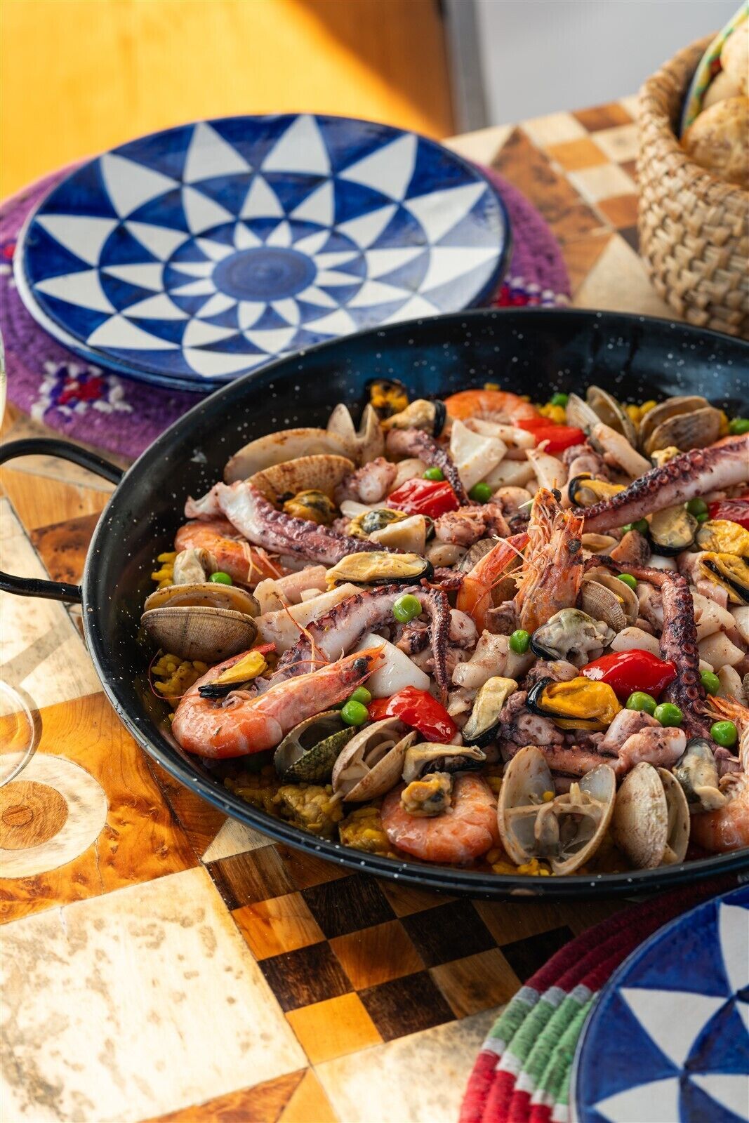 Un piatto di pesce in padella su un tavolo con tovaglia fantasia.