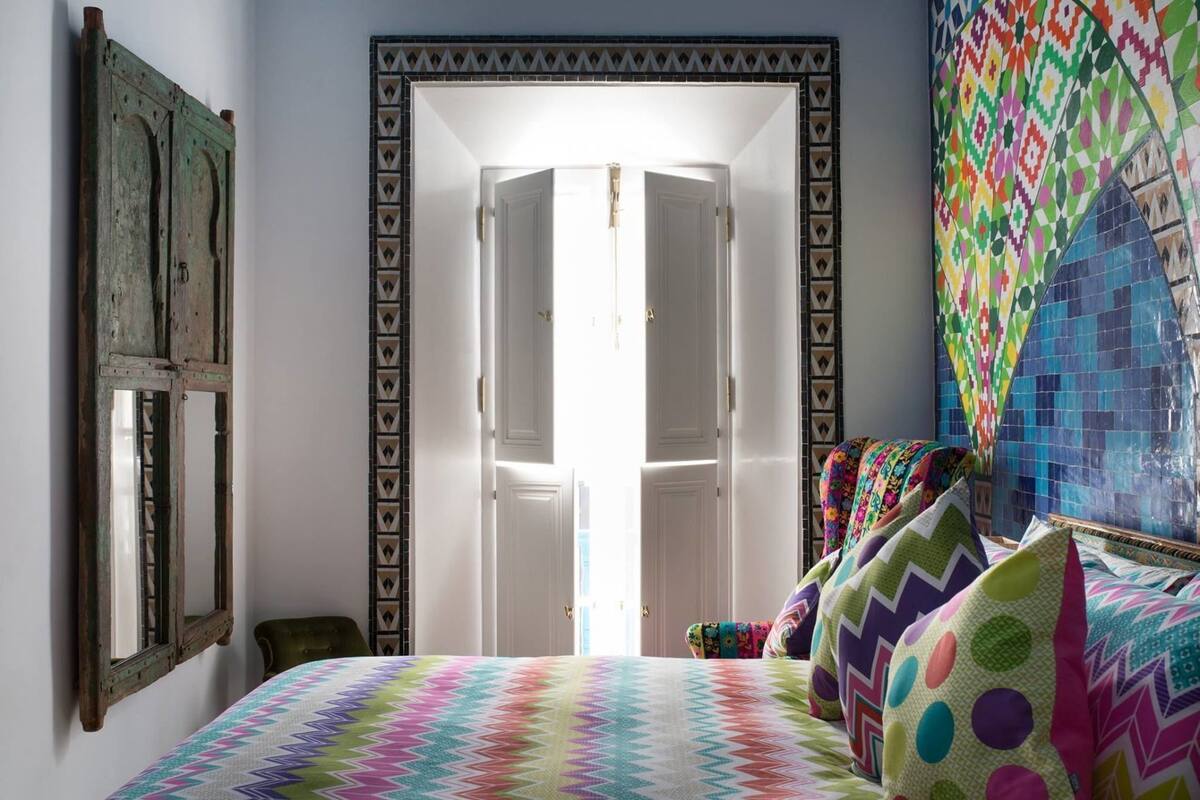 Une chambre à coucher avec un lit, une porte et un mur aux couleurs vives.
