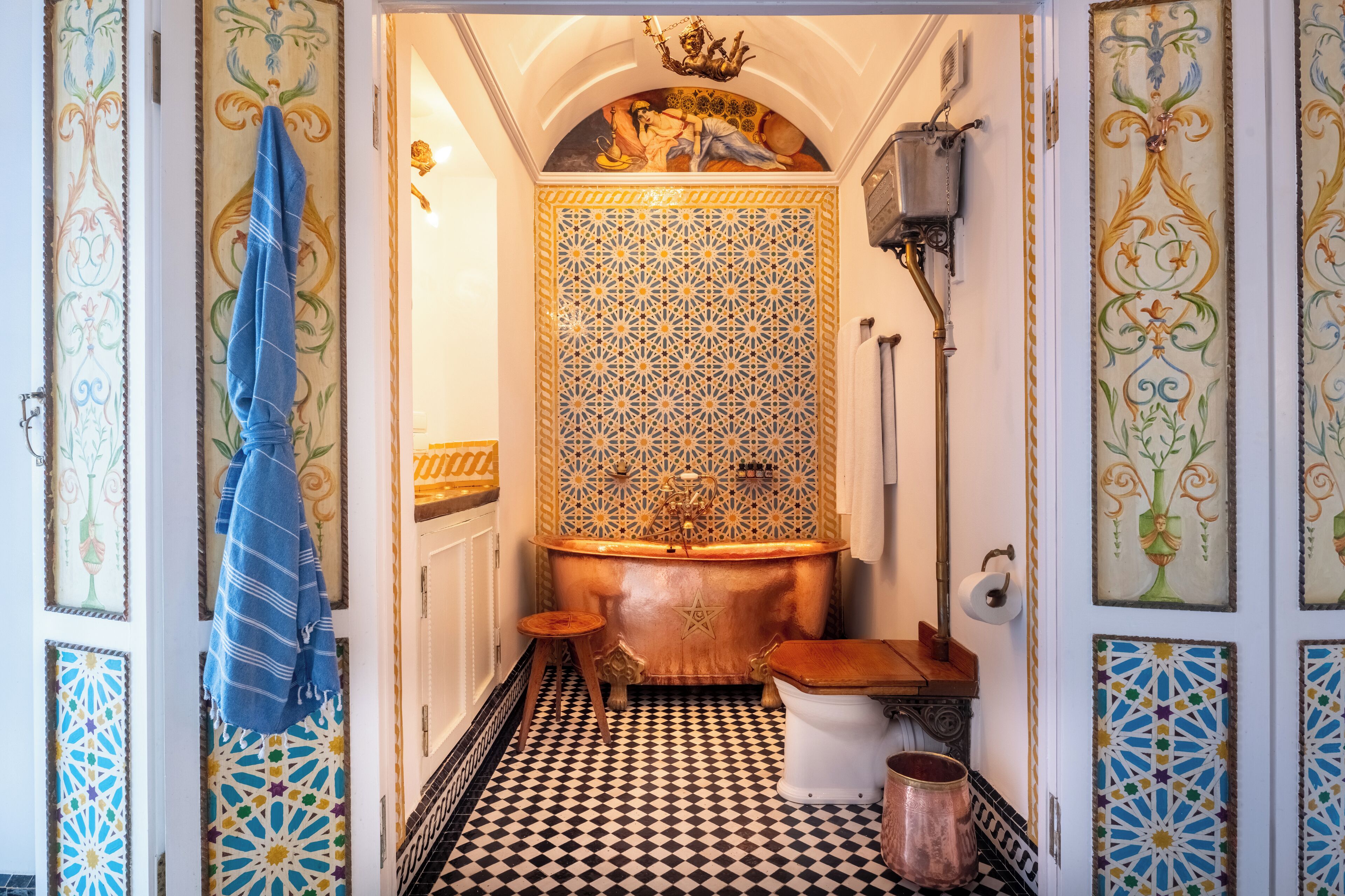 A bathroom with a black and white checkered floor, a copper bathtub, and a wooden toilet.