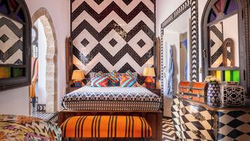 A room with a bed, a bench, and a chest of drawers.