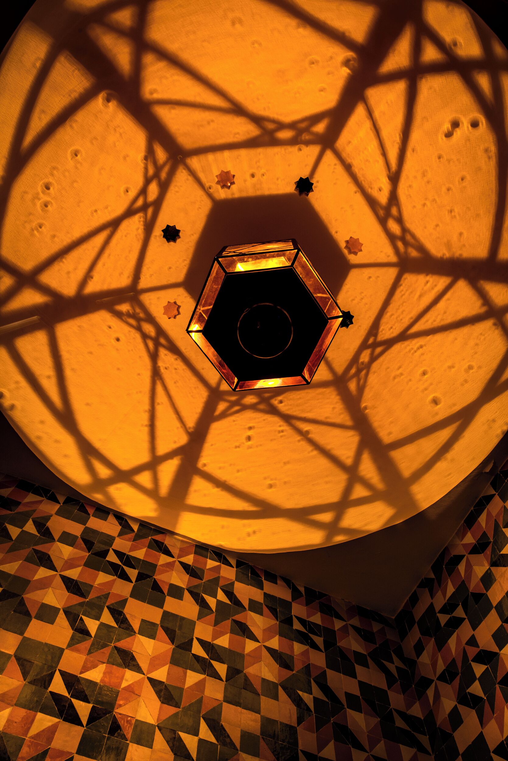 A geometric patterned floor and a hexagonal light fixture casting star-shaped shadows.