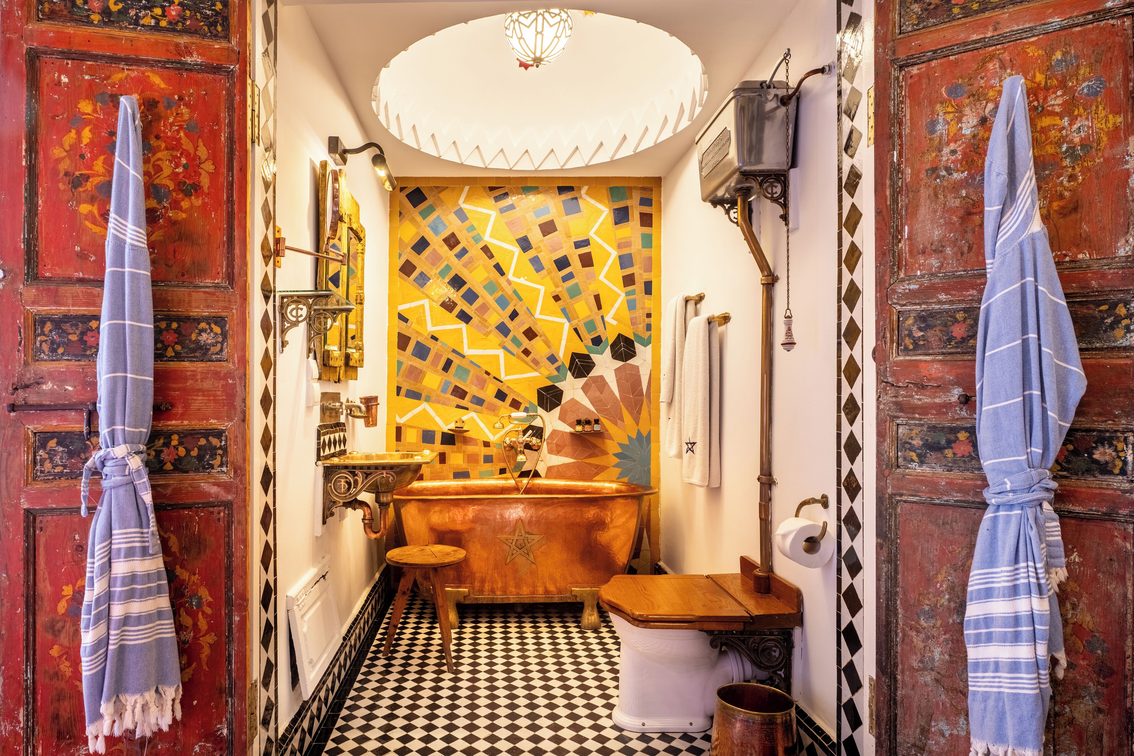 A bathroom with a checkered floor, a star-shaped bathtub, and towels hanging on the walls.