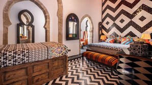 Une chambre avec deux lits, des têtes de lit en bois et un sol à motifs.