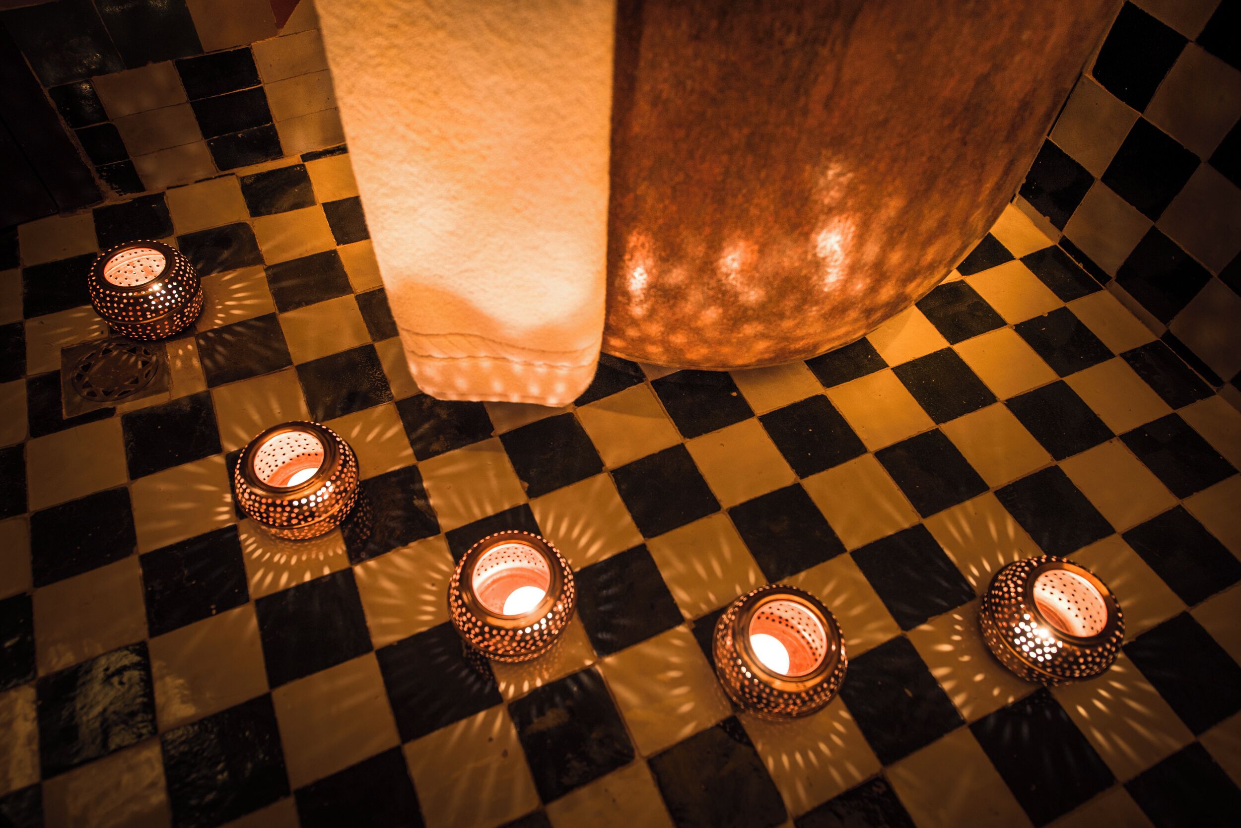 A checkered floor with four lit candles.