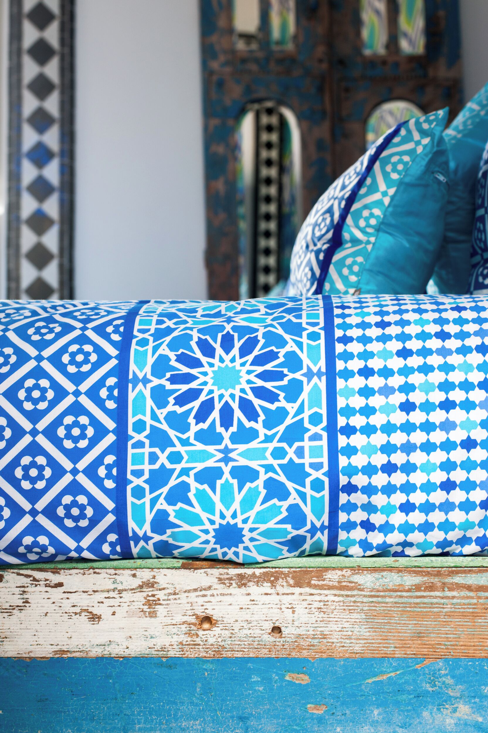 A bed with patterned pillows and a wooden headboard.