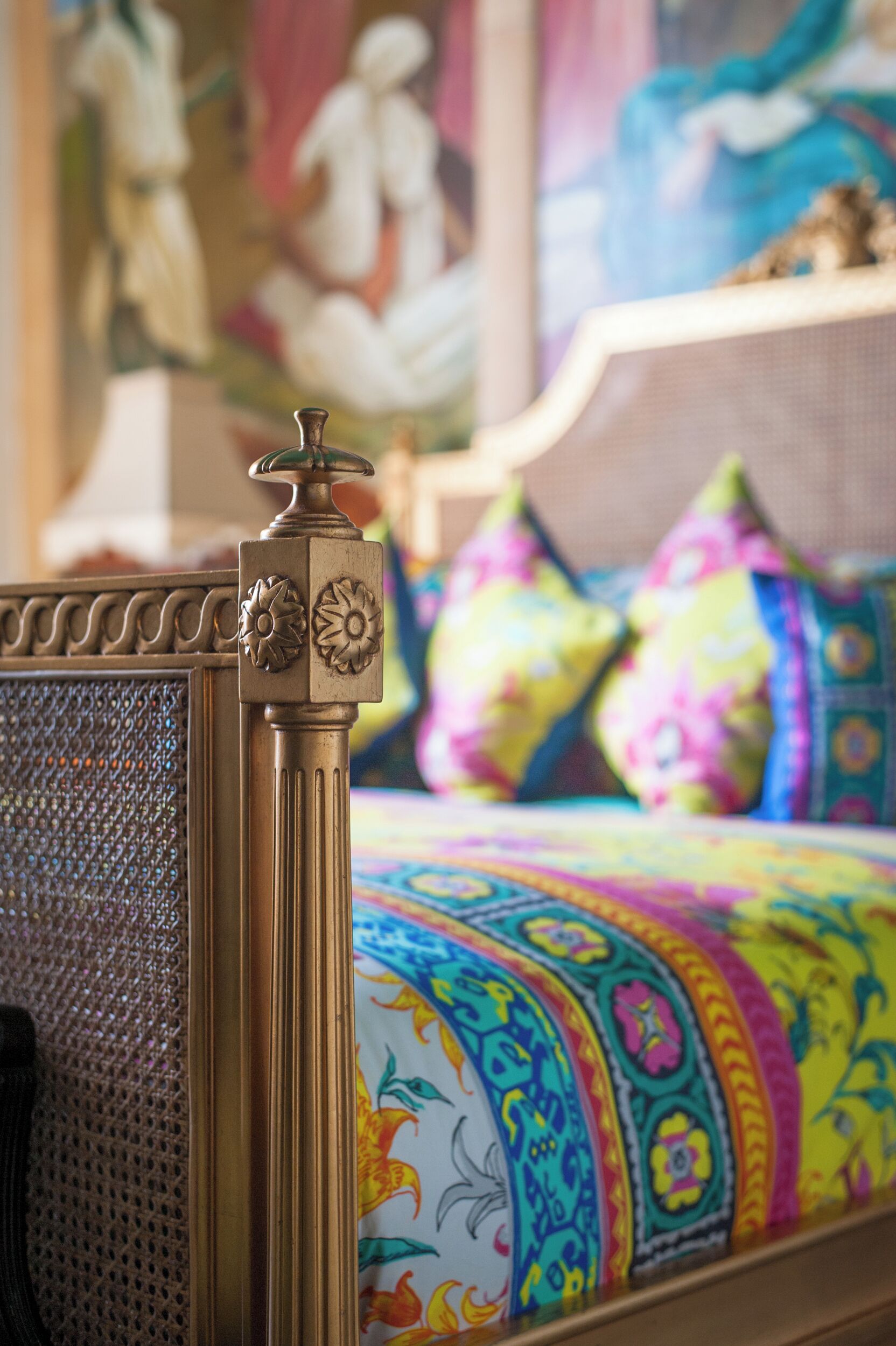 A bed with colorful patterned bedding, a decorative headboard, and a textured side panel.