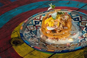 Une assiette colorée sur laquelle est présentée une pièce montée, le tout posé sur une table en bois aux couleurs vives et variées.