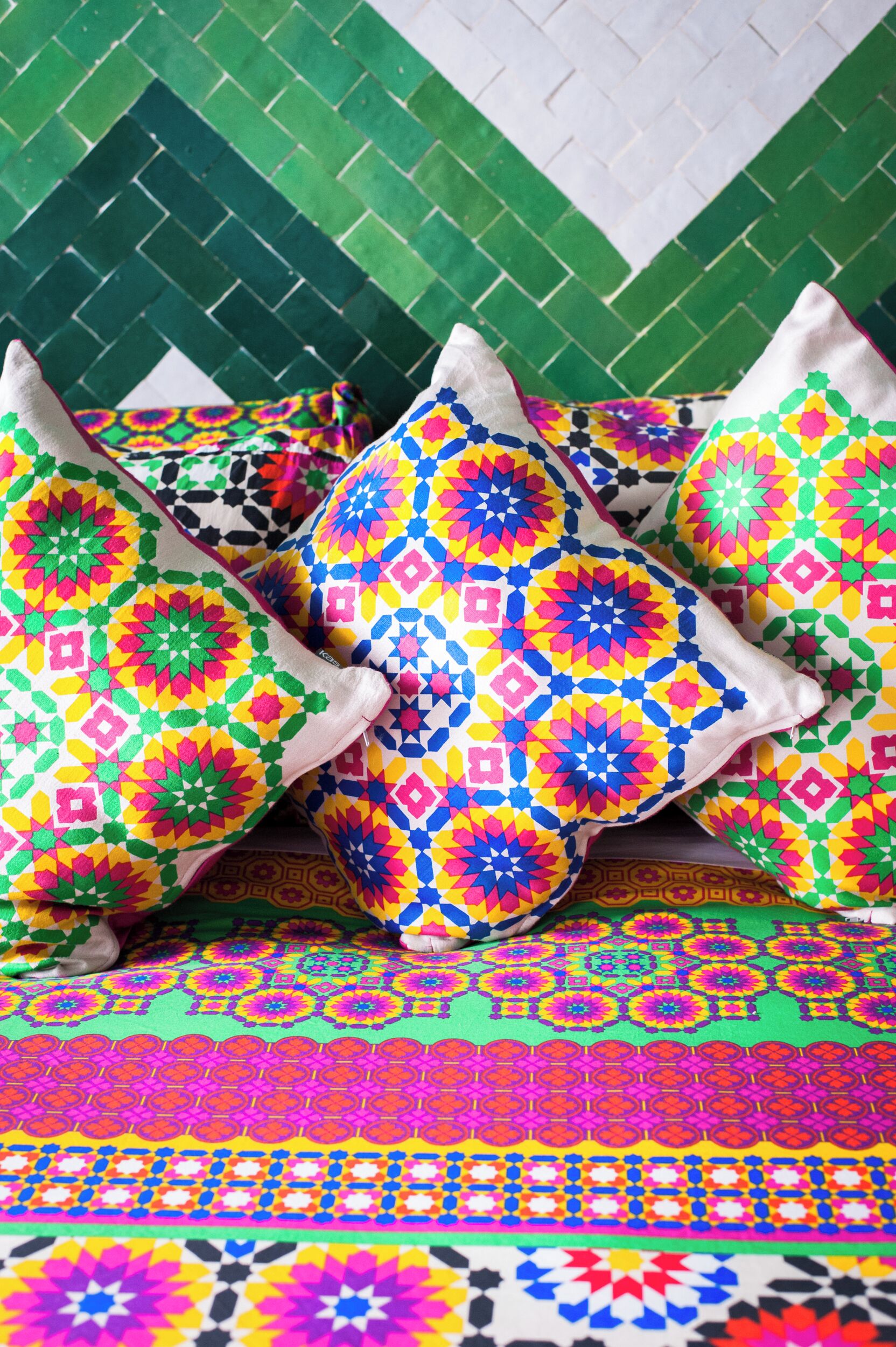 A bed with colorful pillows and a patterned bedspread.