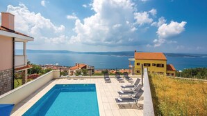 Una piscina con lettini e vista sul mare, sotto un cielo sereno.