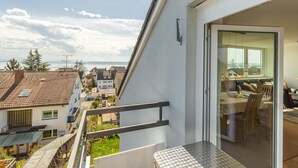 Un balcon doté d’une rambarde en métal, donnant sur un quartier résidentiel et un plan d’eau.