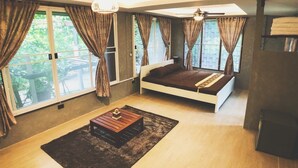 A modern bedroom with a bed, a coffee table, and large windows with curtains.