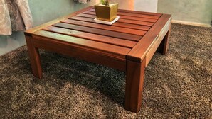 A wooden coffee table with a planter on top, placed on a carpeted floor.
