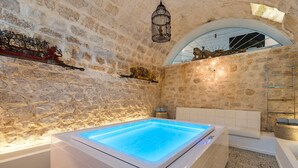 A stone-walled room with a heated floor bath, a white bathtub, and a small shelf with decorative items. - Villa with pool and private wellness area in Scicli, Sicily - 8 pax (Scicli)