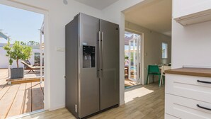 Una cucina moderna con frigorifero in acciaio inossidabile, pavimento in legno e vista sul patio esterno.