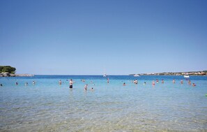 A beach with clear shallow waters and a sailboat in the distance. - Lovely home in Petrcane (Petrcane)