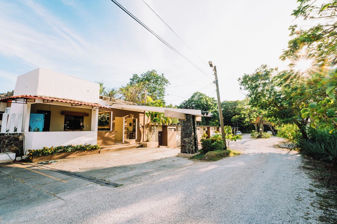 A two-story house with a covered porch, a stone pillar, and a gravel driveway.