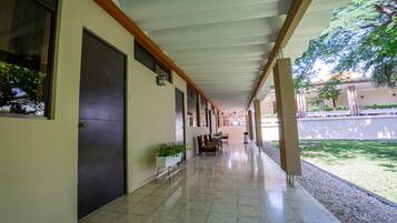 A covered corridor with tiled flooring, a bench, and potted plants.