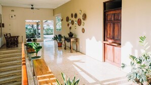A spacious hallway with a wooden bench, potted plants, and a ceiling fan. - Hotel Diriá Santa Cruz (Santa Cruz)