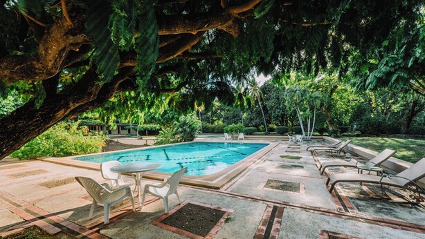 A pool area with a rectangular pool, lounge chairs, and a table with chairs. - Hotel Diriá Santa Cruz (Santa Cruz)