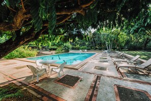 A pool area with a rectangular pool, lounge chairs, and a table with chairs. - Hotel Diriá Santa Cruz (Santa Cruz)