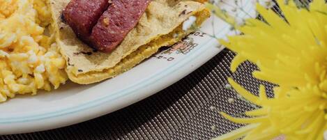 Un plato con arroz negro, plátanos fritos, huevos revueltos y una rebanada de tostada con salchicha.