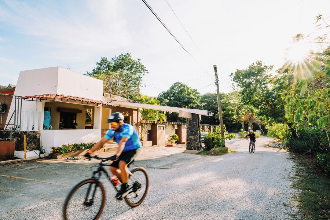 A cyclist riding on a gravel path in a residential area with houses and greenery.