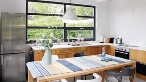 A modern kitchen with a large window, stainless steel appliances, and a dining area with a table and chairs.
