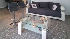 Una sala moderna con una mesa de centro de vidrio, un sofá y dos taburetes de bar.