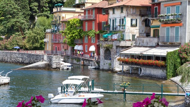 Un canal bordé de bateaux, un pont de pierre et des bâtiments aux couleurs vives, dotés de balcons.