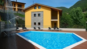 Un bâtiment moderne doté d’une piscine, de chaises longues et d’une cascade décorative.