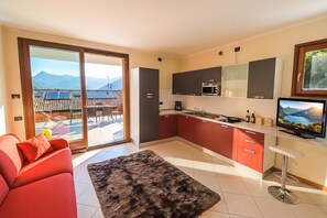 A modern kitchen with a large window, a dining area with a red sofa, and a view of mountains.