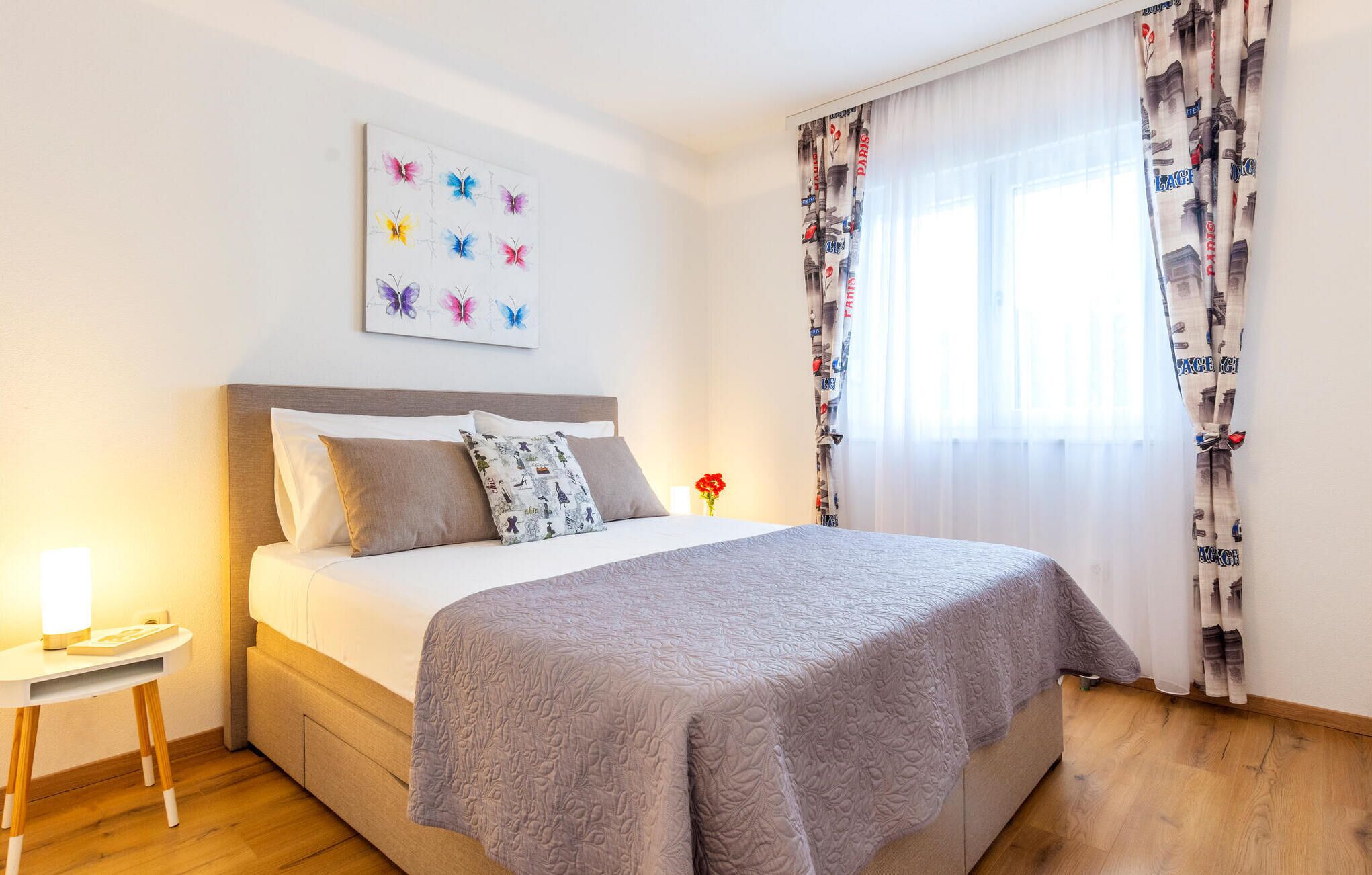 A neatly arranged bedroom with a bed, a bedside table, a lamp, and a wall-mounted artwork.