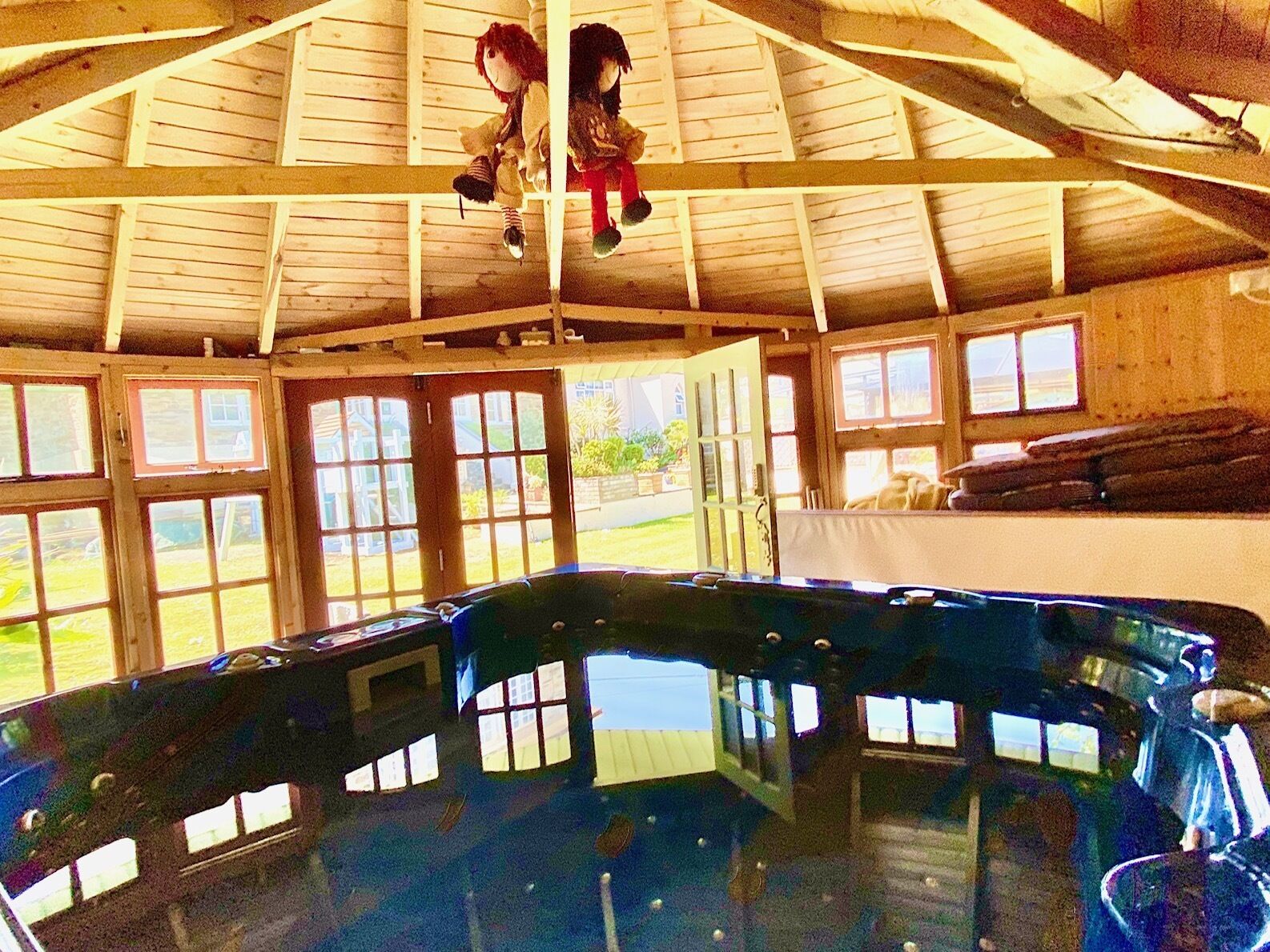 A large indoor swimming pool with a wooden ceiling and multiple windows.