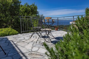 An outdoor patio with a stone floor, metal railing, and a table with a cake stand. - TOP OFFER-Charming cottage with heated pool in a quiet location and sea view (Makarska)