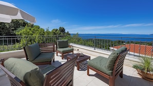 Een terras met houten meubels en uitzicht op zee.