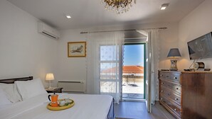 Een hotelkamer met een bed, nachtkastje met lamp, een kapstok en een televisie.