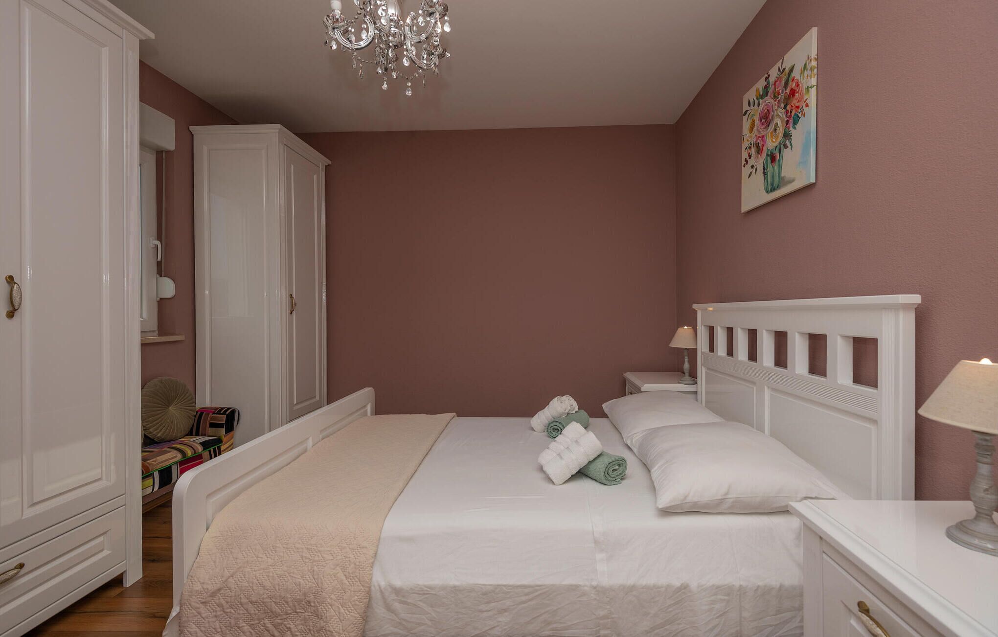 Une chambre à coucher comprenant un lit, une table de chevet, une lampe, une armoire et un lustre.