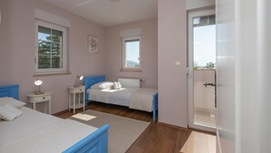 A bedroom with two beds, a bedside table with a lamp, a window, and a door leading to a balcony. - Amazing home in Imotski (Imotski)