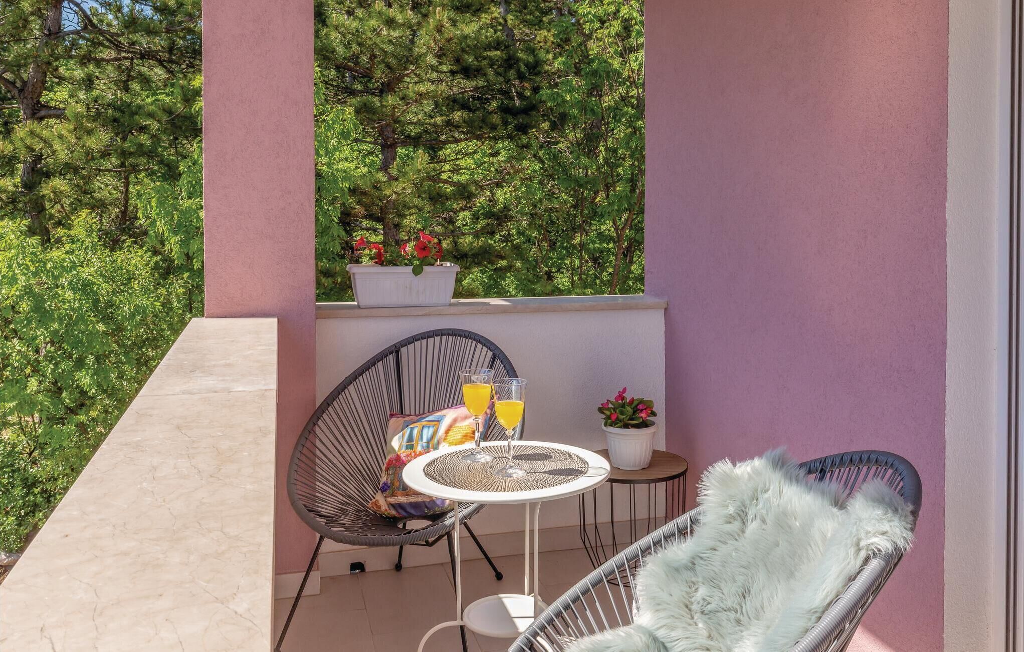A balcony with two wicker chairs, a small round table, and a potted plant.
