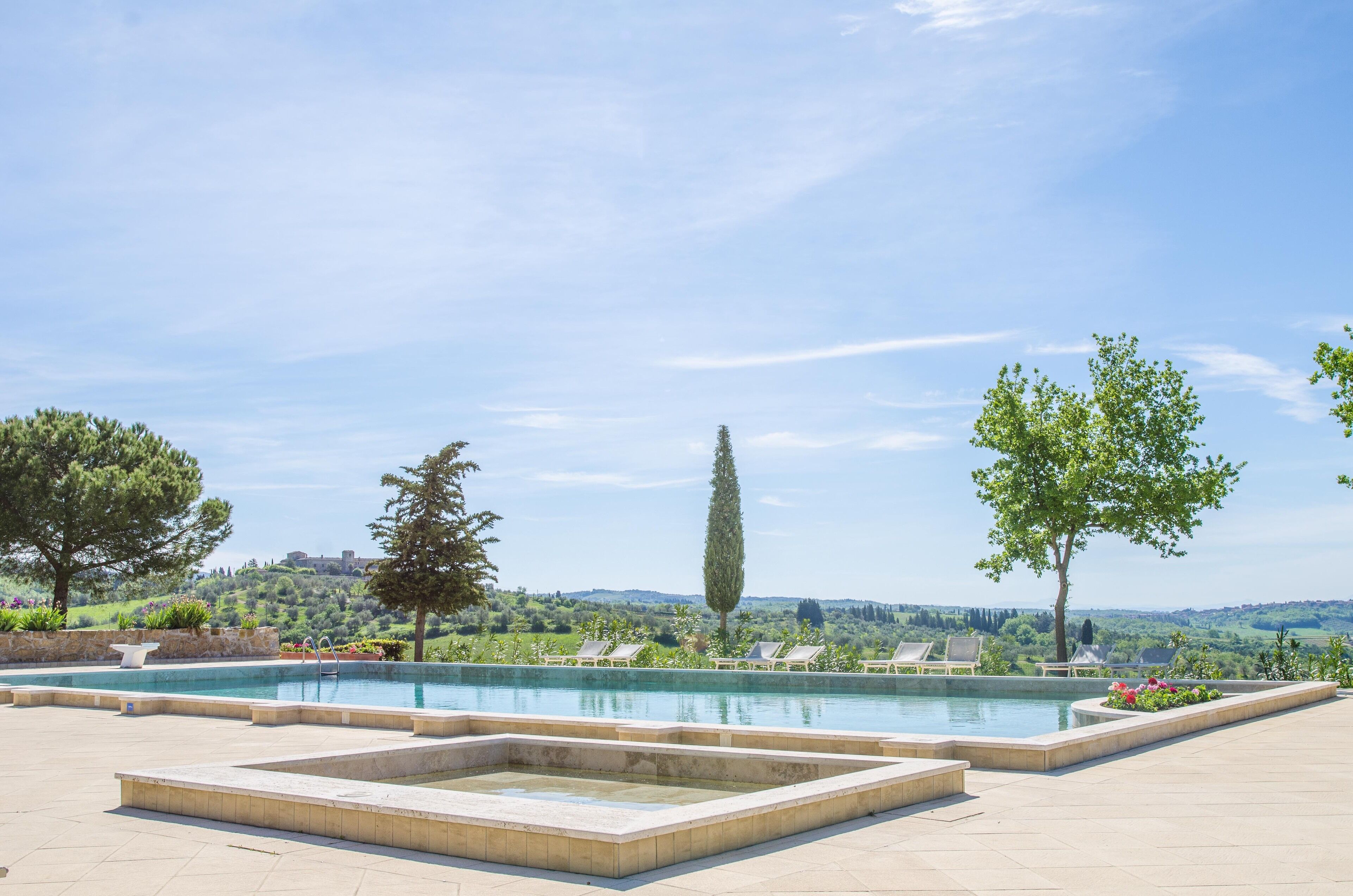 A pool area with a view of a hill and trees.