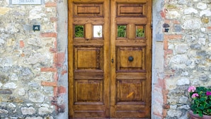 A wooden double door with a stone wall backdrop, a nameplate reading "THE BARN," and a potted plant to the right. - Luxury converted barn with hilltop views in chianti wine region, Tuscany (Castellina in Chianti)