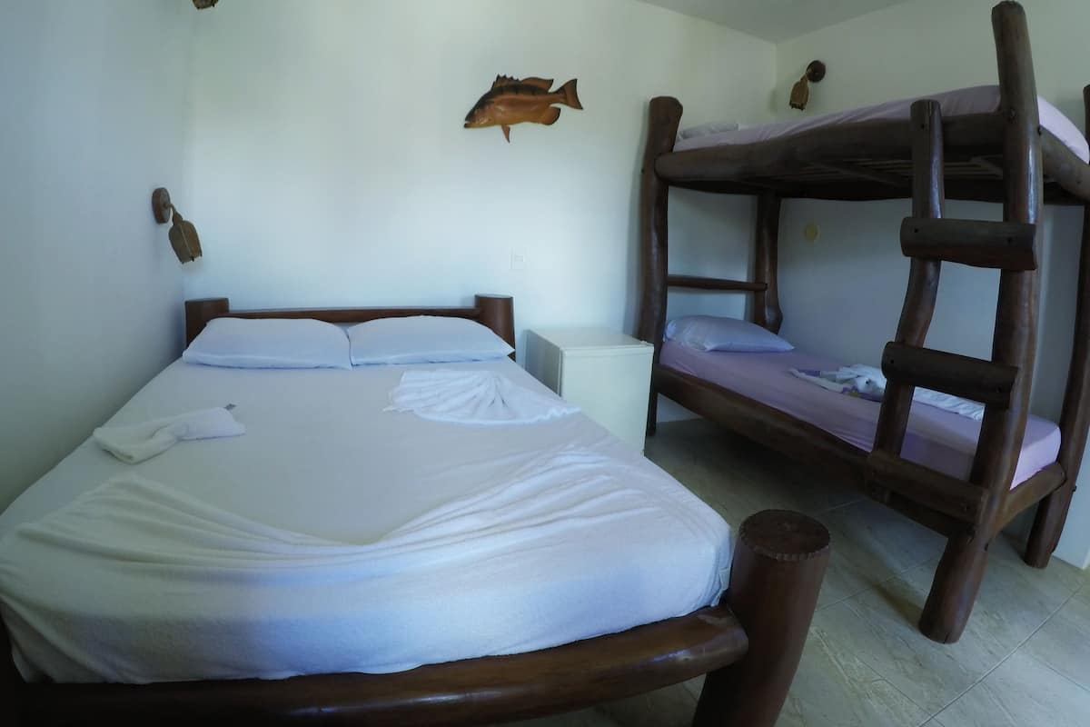 A room with a bunk bed and a single bed, both with white bedding.