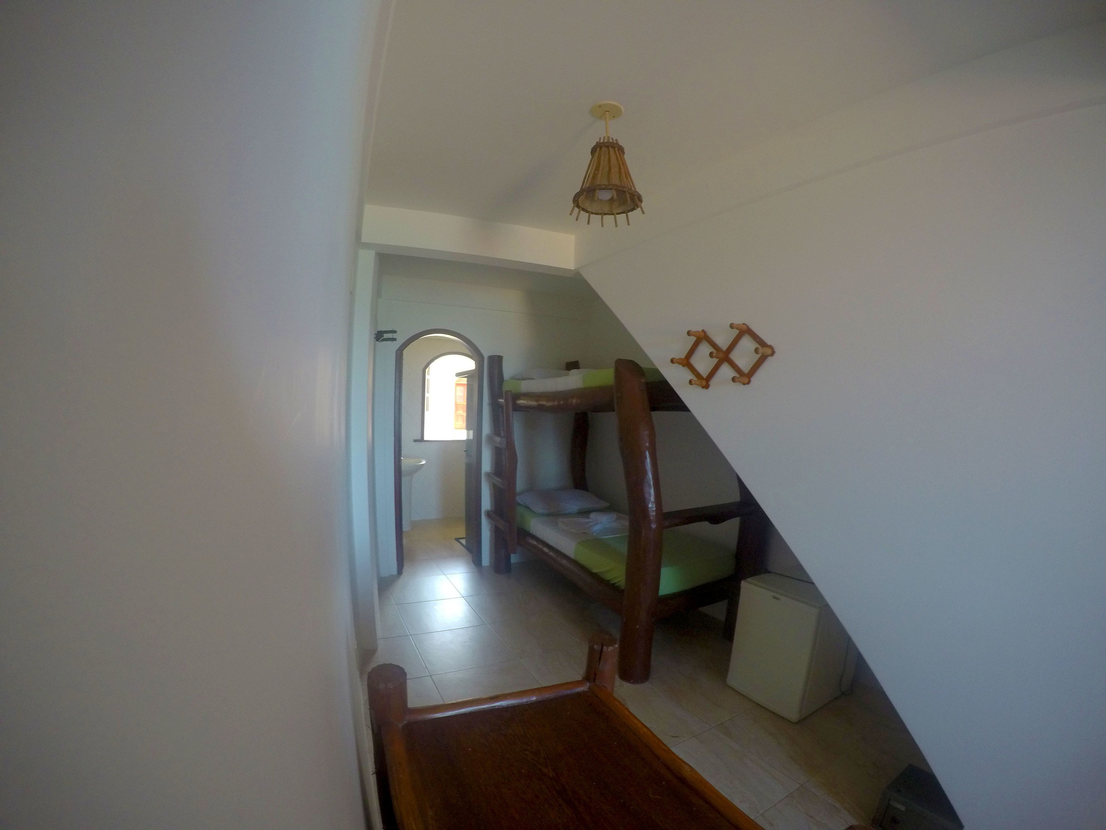A narrow hallway with a wooden bench, a bunk bed, and a small white appliance on the floor.