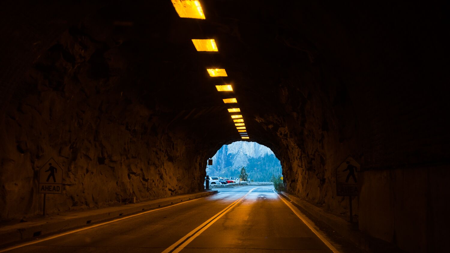 Tunnelin päästä avautuu tie, joka johtaa vuoristomaisemille.
