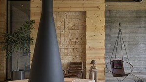 A modern lounge area with a central fireplace, wooden seating, and a hanging chair. - AutoCamp Yosemite (Mariposa)