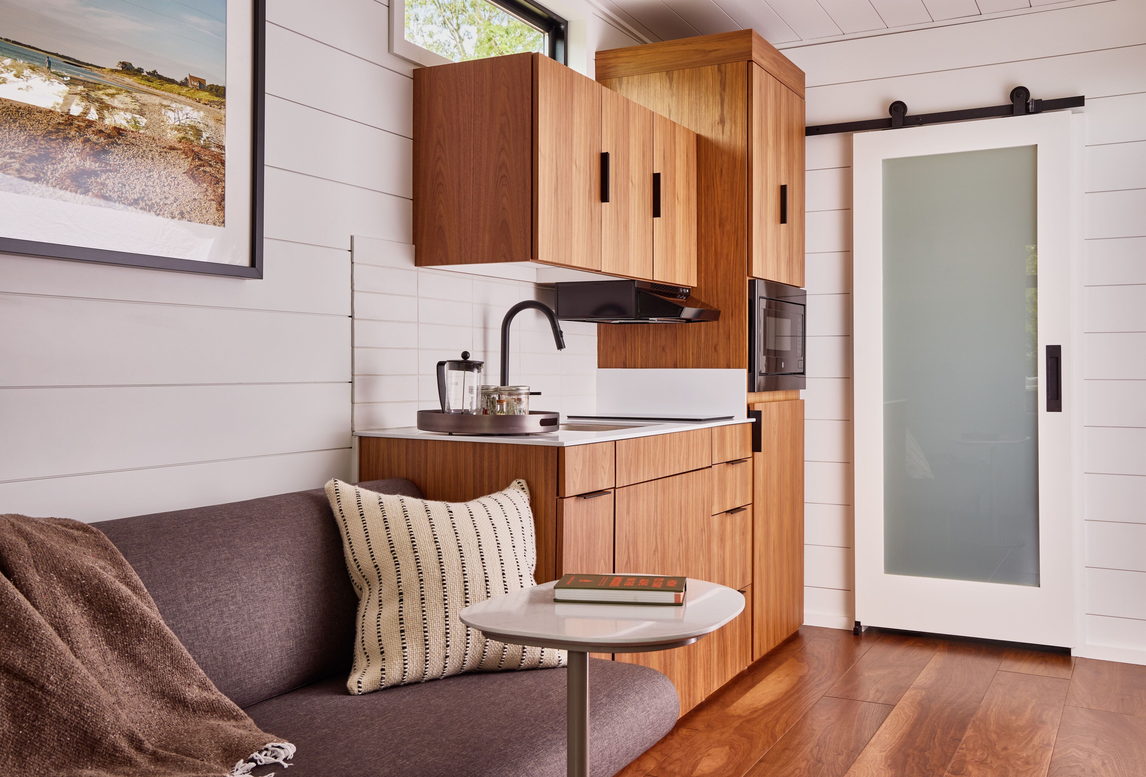 A modern kitchen with wooden cabinets, a built-in oven, and a glass door.