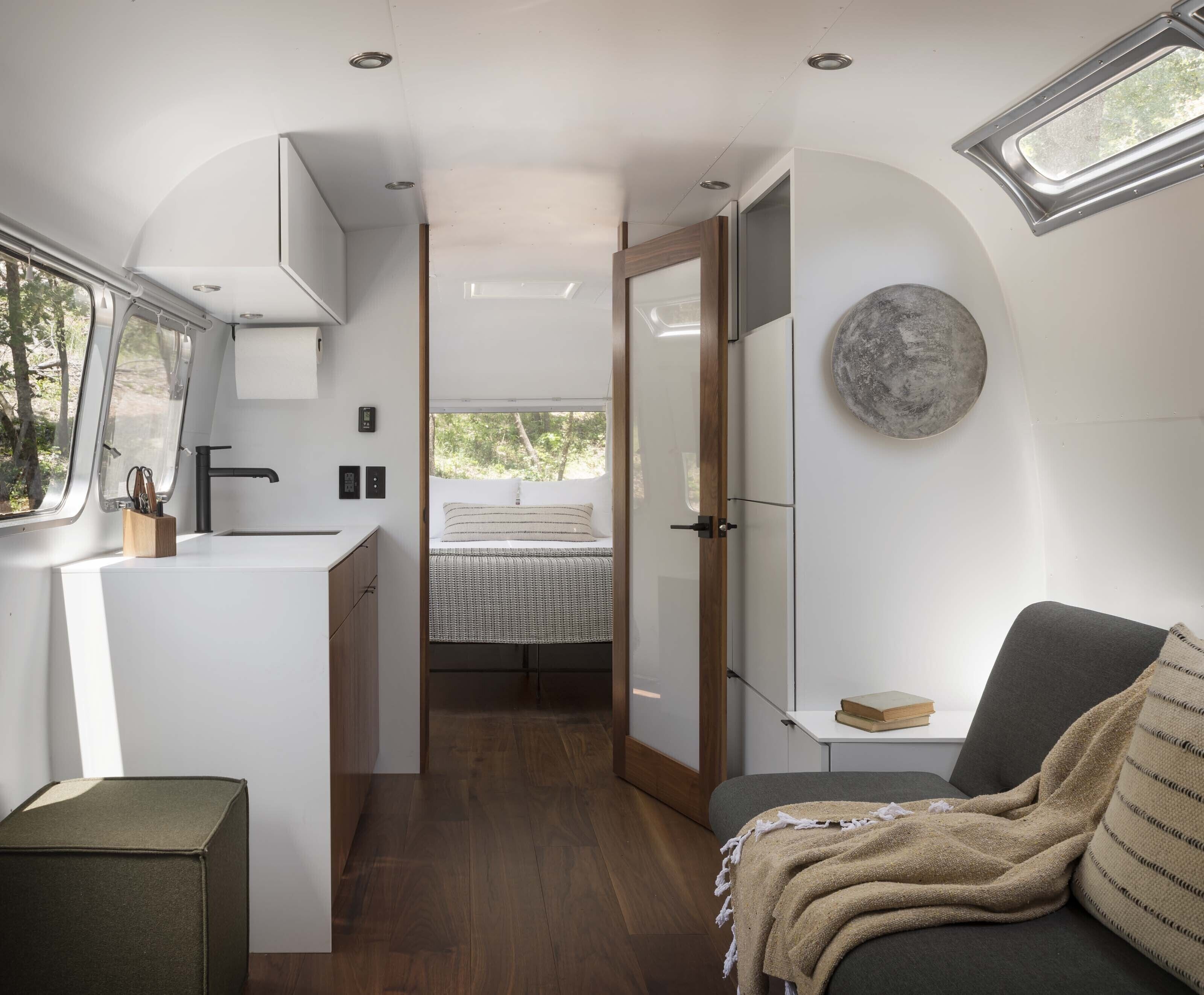 Interior compacto de autocaravana con kitchenette, cama y zona de estar.