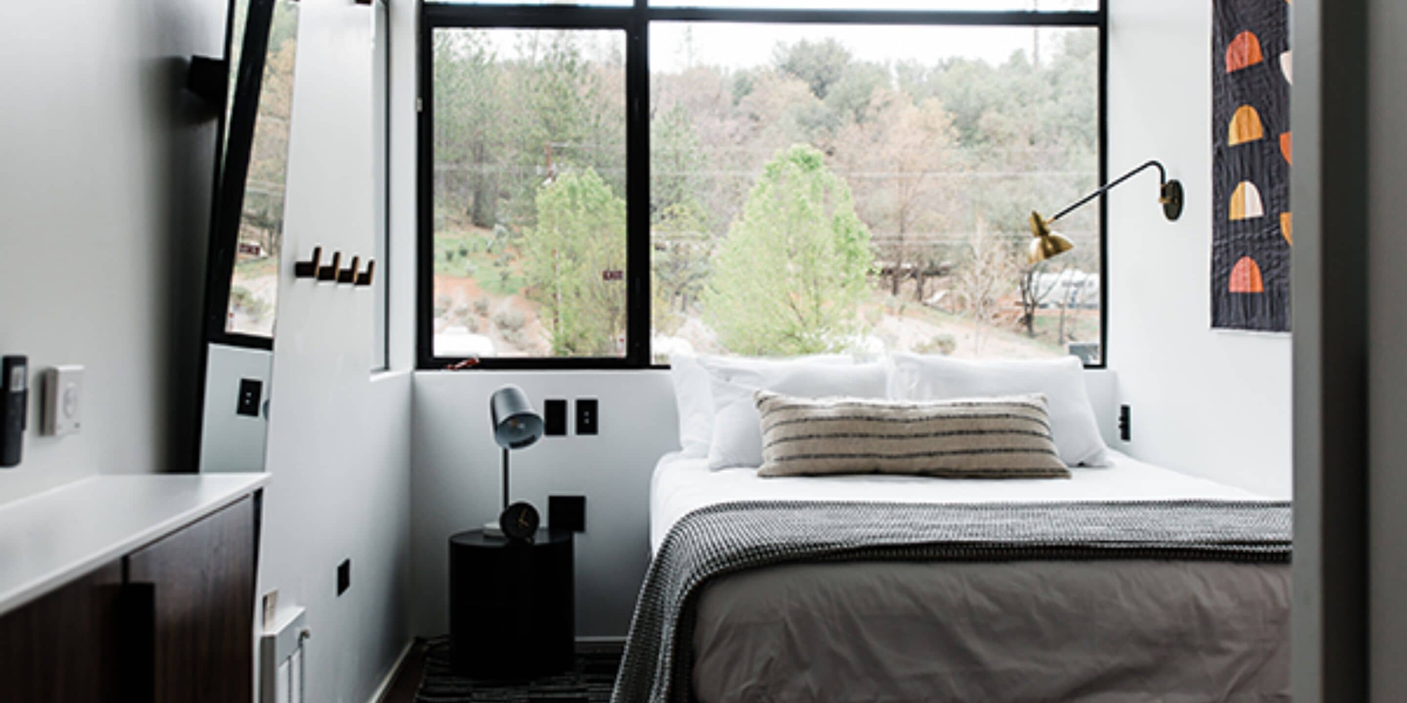 Une chambre à coucher avec un lit, une table de chevet, une fenêtre et une vue sur les arbres.